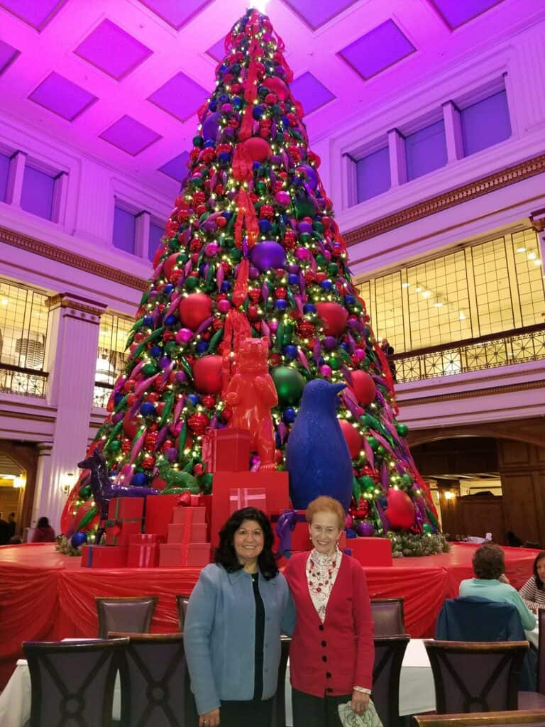 two women standing in front of a tall Christmas tree