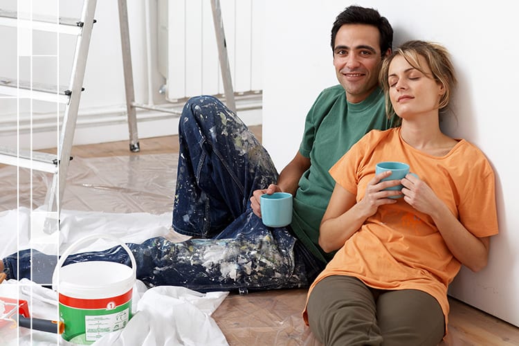 pareja pintando su casa tomando un descanso