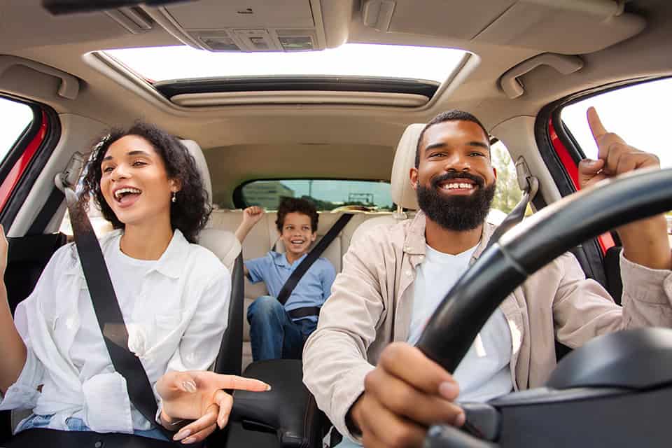Happy family enjoying a road trip in a car, smiling and having fun together.