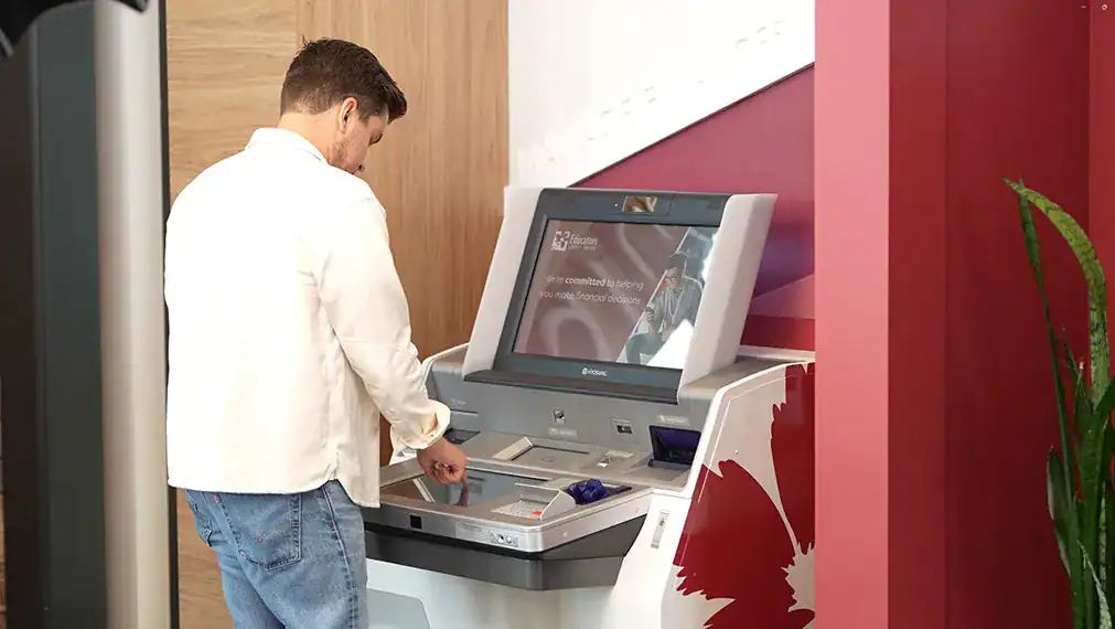 Person using a Teller-Operated Machine (TOM) for banking transactions.