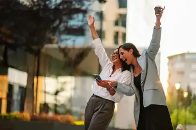 Two women celebrating the news of A Top Choice Of Milwaukee reward on their phone, smiling and raising hands.