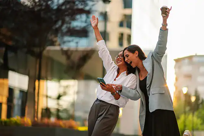 Two women celebrating the news of A Top Choice Of Milwaukee reward on their phone, smiling and raising hands.