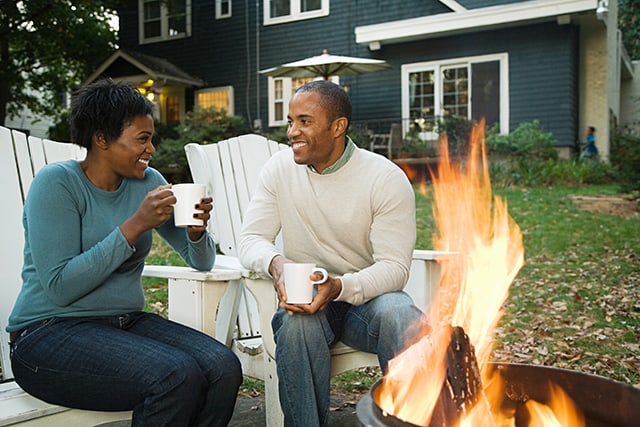 couple holding coffee cups around a fire