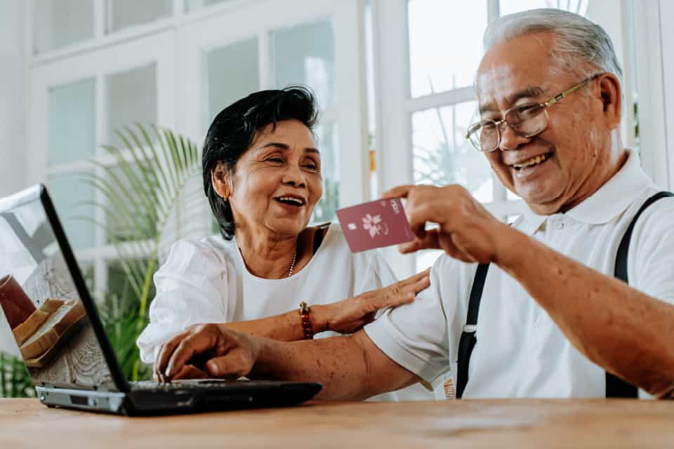 older couple holding credit card smiling