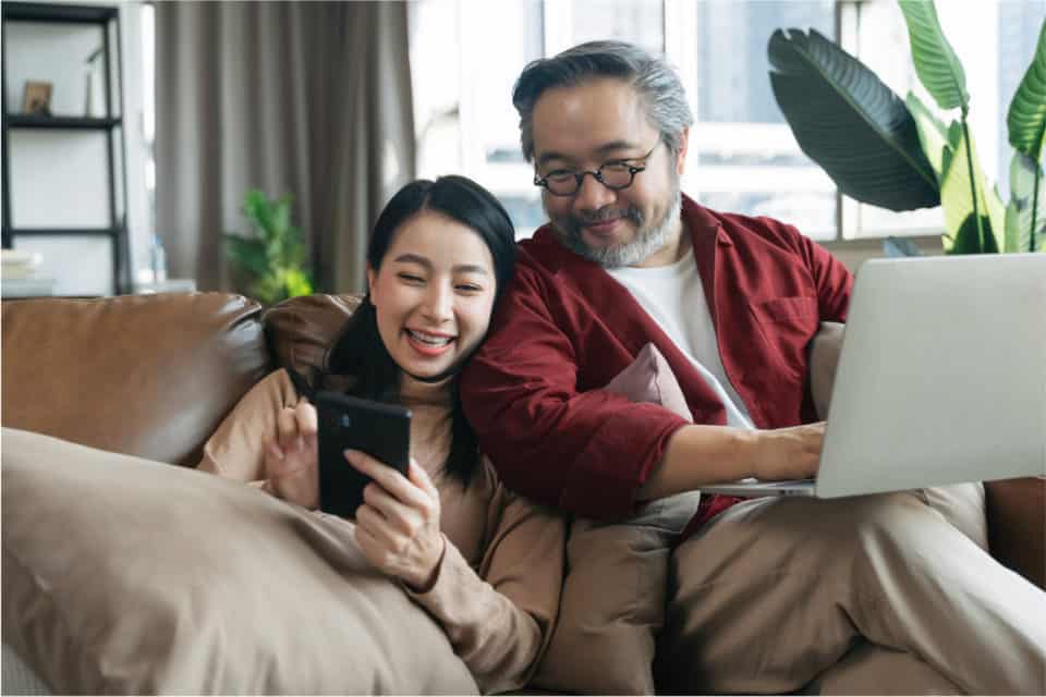 mujer y hombre juntos en un sofá con su teléfono y computadora