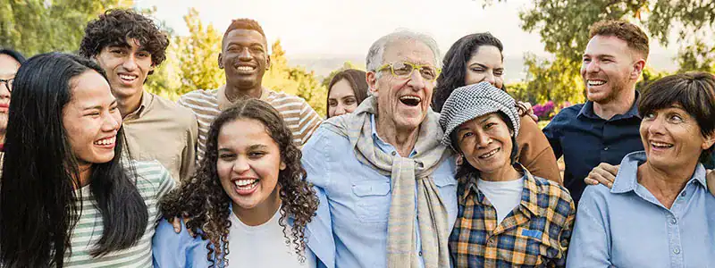 Diverse group of smiling people enjoying outdoor event that shares knowledge about the benefits of a credit union vs a bank.