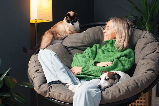 Woman sitting with cat and dog as we discuss costs of a pet