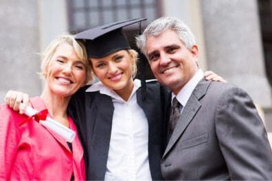 Adolescente con gorra de graduación sonriendo con sus padres.
